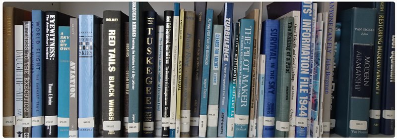 a shelf of aviation related books at the National Model Aviation Museum